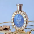 Victoria Lattafa golden perfume on display surrounded gold accessories closeup blue glass