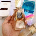 Lattafa Ana Abiyedh Leather 60ml — White perfume box and glass bottle with gold accents and Arabic calligraphy, showing the product packaging and bottle design. | Kotak minyak wangi putih dan botol kaca dengan aksen emas dan kaligrafi Arab, menunjukkan pembungkusan produk dan reka bentuk botol.