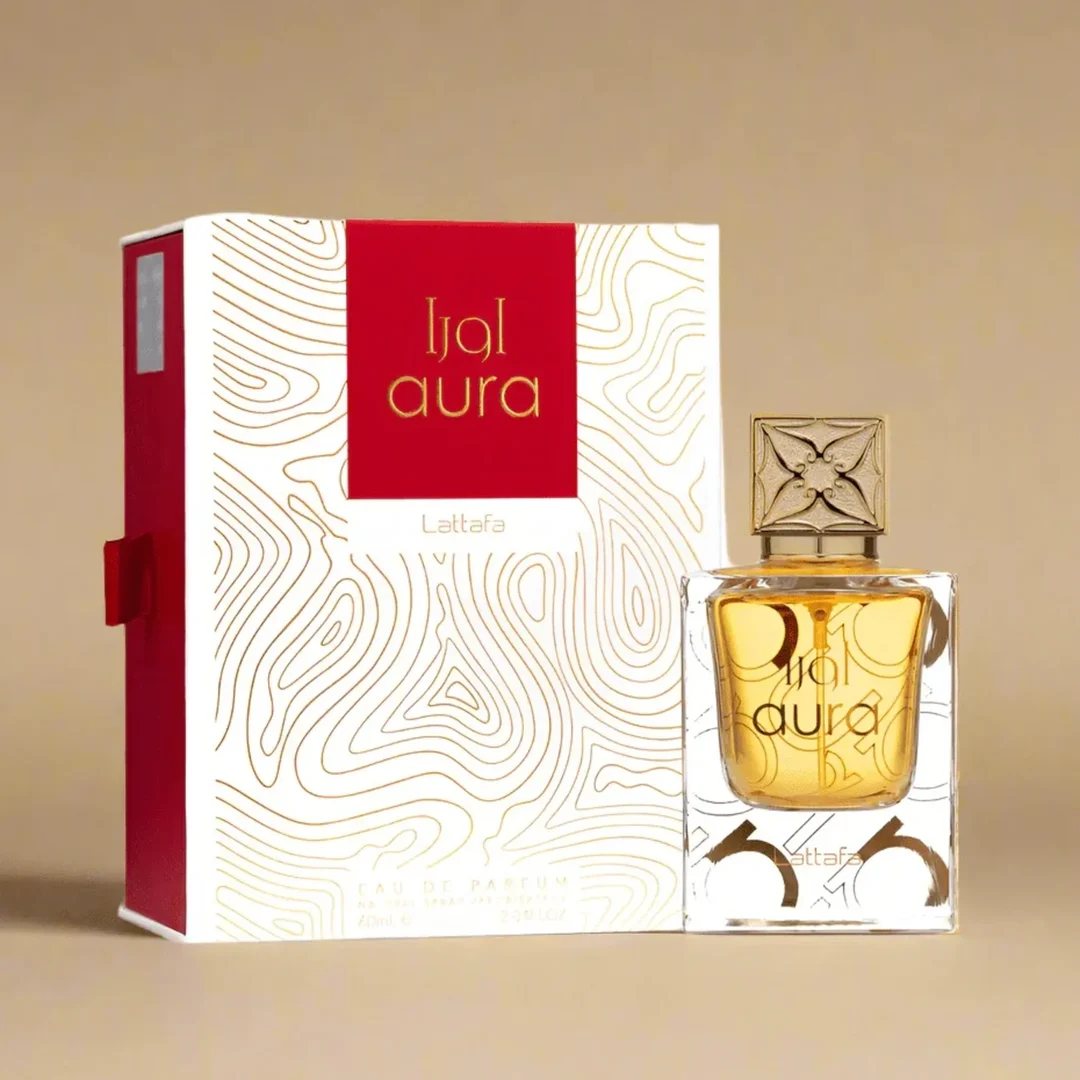 Lattafa Aura Lattafa 60ml EDP — A clear glass perfume bottle with gold liquid and a decorative gold cap sits next to its white and red box with gold topographic line art. | Lattafa Aura Lattafa 60ml EDP — Botol minyak wangi kaca jernih dengan cecair emas dan penutup emas hiasan terletak di sebelah kotak putih dan
