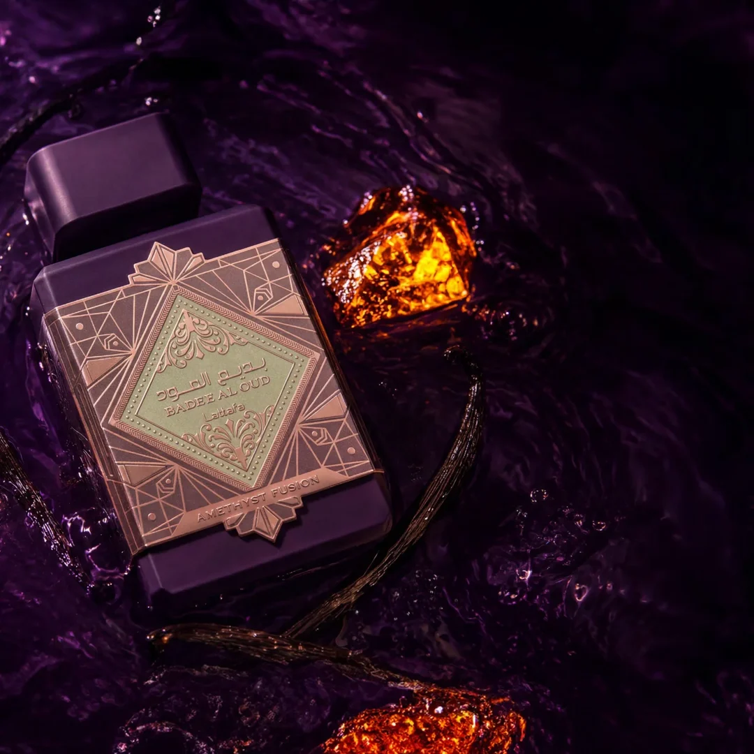 Lattafa Bade'e Al Oud Amethyst Fusion 100ml — A purple perfume bottle with a dark grey cap and a gold and light green geometric label. | Lattafa Bade'e Al Oud Amethyst Fusion 100ml — Botol minyak wangi ungu dengan penutup kelabu gelap dan label geometri emas dan hijau muda.