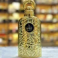 Lattafa Bayaan Eau De Parfum 100ml by Lattafa — A golden perfume bottle with intricate Arabic calligraphy design, presented in a white box with a matching golden outer sleeve featuring similar calligraphy. | Lattafa Bayaan Eau De Parfum 100ml by Lattafa — Botol minyak wangi emas dengan reka bentuk kaligrafi Arab yang
