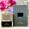 Rave Pure Desire Gold edp dalam botol hitam atas meja, dekat bunga