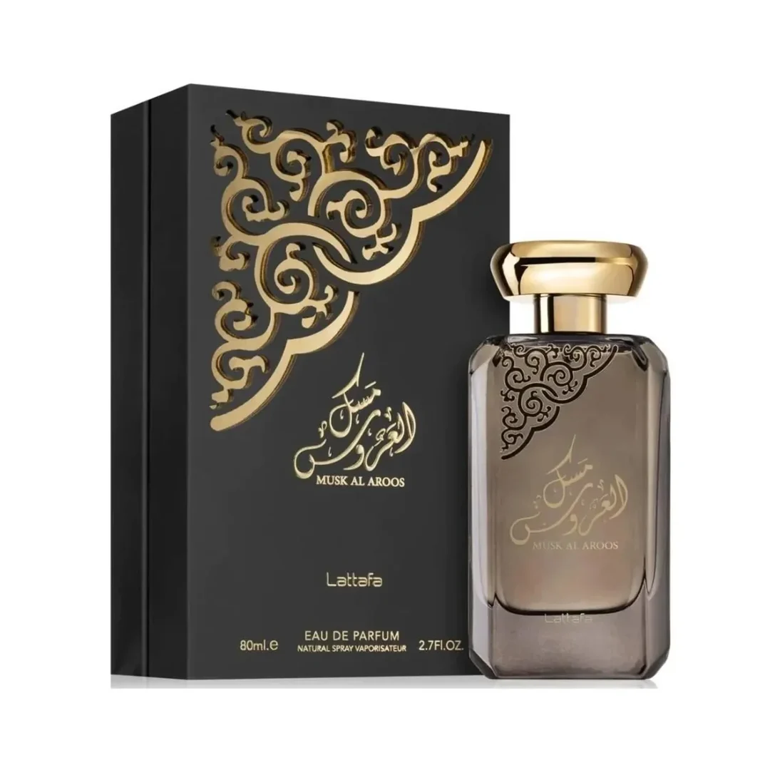 Lattafa Musk Al Aroos — A dark blue perfume bottle with gold Arabic calligraphy and 'MUSK AL AROOS LATTAFA' text, presented in an open dark blue gift box with a black velvet insert. | Lattafa Musk Al Aroos — Botol minyak wangi biru gelap dengan kaligrafi Arab emas dan teks 'MUSK AL AROOS LATTAFA', dipersembahkan dalam
