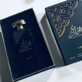 Lattafa Musk Al Aroos — A dark blue perfume bottle with gold Arabic calligraphy and 'MUSK AL AROOS LATTAFA' text, presented in an open dark blue gift box with a black velvet insert. | Lattafa Musk Al Aroos — Botol minyak wangi biru gelap dengan kaligrafi Arab emas dan teks 'MUSK AL AROOS LATTAFA', dipersembahkan dalam