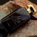 Lattafa Musk Al Aroos — A dark blue perfume bottle with gold Arabic calligraphy and 'MUSK AL AROOS LATTAFA' text, presented in an open dark blue gift box with a black velvet insert. | Lattafa Musk Al Aroos — Botol minyak wangi biru gelap dengan kaligrafi Arab emas dan teks 'MUSK AL AROOS LATTAFA', dipersembahkan dalam