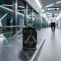Shaghaf Man Asdaaf Lattafa black cologne on metal luggage carousel airport terminal hallway