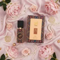 Ajwad Lattafa edp unisex fragrance pink background flowers pearls gold accessories flatlay