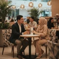 Couple sitting holding Ameer Al Oudh Intense Lattafa edp fragrance in cafe setting