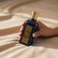 Hand holding Azeezah Lattafa blue gold fragrance elegant closeup side view