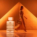 Woman walking past Badee Al Oud Honor Glory Lattafa pyramid background orange lighting