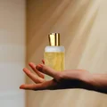Hand holding Ajayeb Dubai Portrait Lattafa edp yellow liquid gold cap closeup