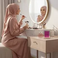 Woman in hijab applying makeup beside Charm LaMuse Lattafa edp vanity table
