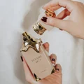 Hands holding Eclaire Lattafa beige gold fragrance Malaysia white background closeup