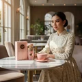 Woman in traditional dress sitting holding Haya Lattafa perfume pink fragrance bottles
