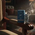 Hayaati Al Maleky Lattafa perfume in blue pack on chair side table smoke rising