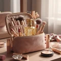 Mazaaji Lattafa edp gold surrounded makeup brushes pink bag wooden tabletop closeup