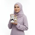 Woman in hijab holding Musk Mood Lattafa unisex fragrance white background closeup side