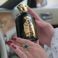 Nasheet Lattafa edp unisex black glass elegant gold cap held hands closeup