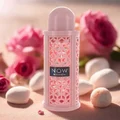 Now Women Rave Lattafa perfume bottle surrounded pink roses white bath bombs beige