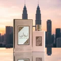 Ameerat Al Arab Prive Rose Lattafa gold perfume bottles displayed outdoors evening skyline