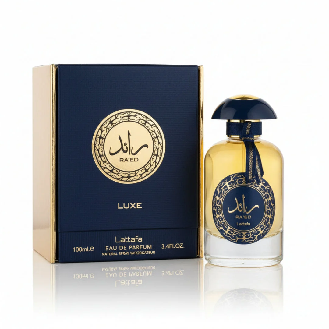 Raed Luxe Lattafa perfume bottle beside navy blue packaging white background closeup side view gold accents