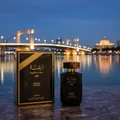 Lattafa Raghba for Men edp beside its packaging at dusk cityscape waterfront bridge view