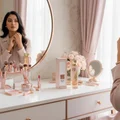 Woman applying makeup in front of Reve Rose Vurv Lattafa perfume on vanity table closeup