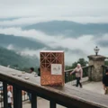 Shahd Lattafa perfume packaging on wooden railing overlooking mountainside landscape cloudy sky
