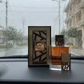 Lattafa simply oud eau de parfum on car dashboard rainy day view outside window glass