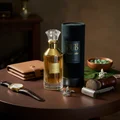 Lattafa Velvet Oud unisex perfume bottle on table surrounded by accessories leather wallet watch shaver brush green beads