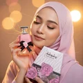 Woman in pink hijab holding Washwasha Lattafa perfume closeup shot bokeh background softly lit