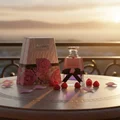 Lattafa washwasah pink fragrance in elegant glass on table surrounded raspberries petal sunset view outside