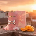 Yara Lattafa pink perfume bottle on stone surface surrounded sliced mango flowers sunset background