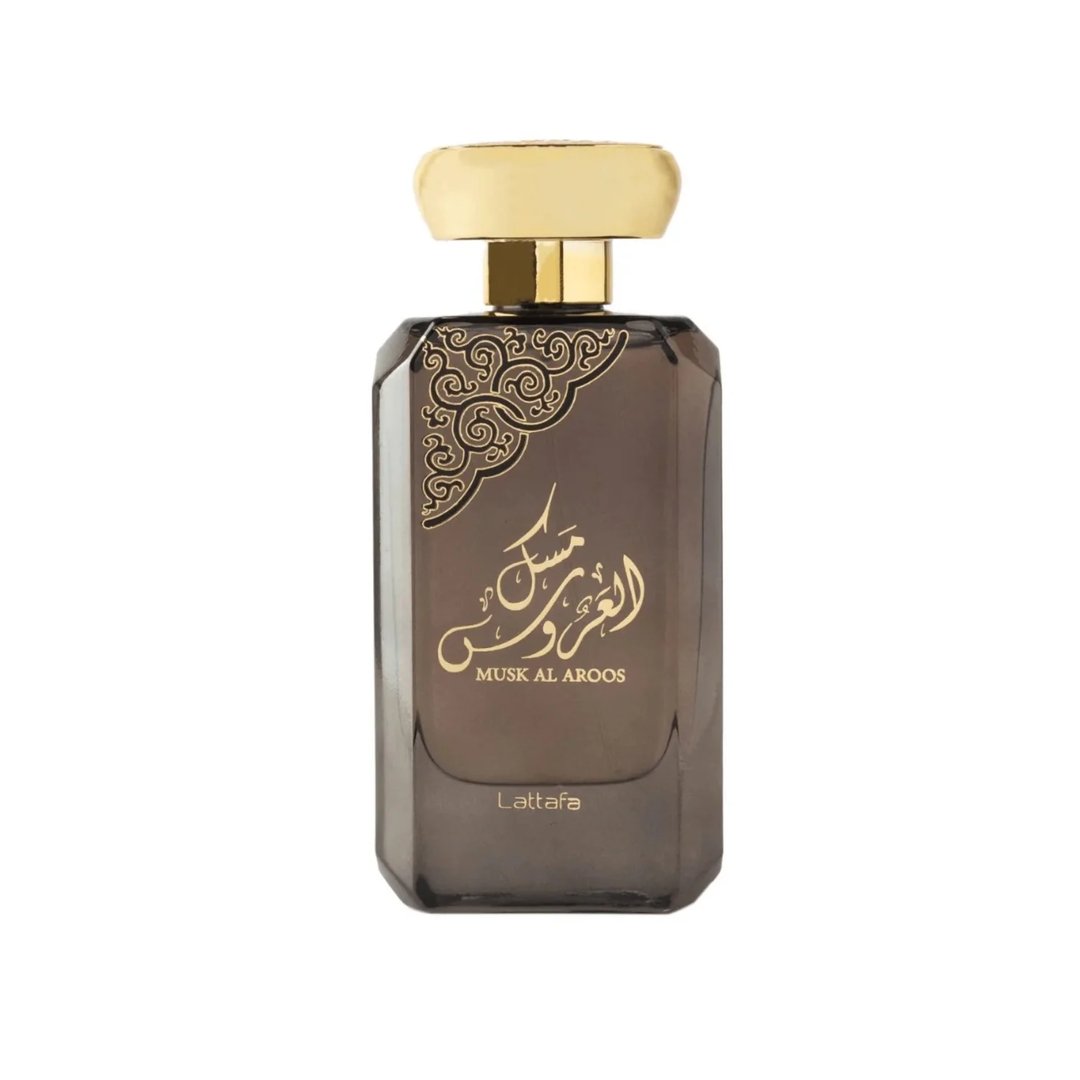 Lattafa Musk Al Aroos — A dark blue perfume bottle with gold Arabic calligraphy and 'MUSK AL AROOS LATTAFA' text, presented in an open dark blue gift box with a black velvet insert. | Lattafa Musk Al Aroos — Botol minyak wangi biru gelap dengan kaligrafi Arab emas dan teks 'MUSK AL AROOS LATTAFA', dipersembahkan dalam