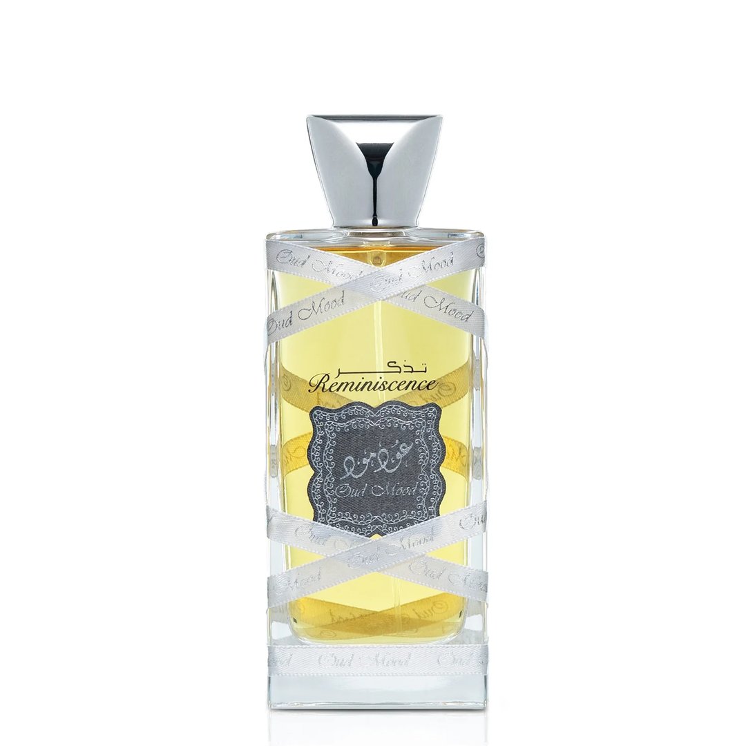 Lattafa Oud Mood Reminiscence 100ml — A cylindrical grey box with silver ornate patterns and a silver ribbon handle stands next to a clear glass perfume bottle with a silver cap, wrapped in white ribbon. | Lattafa Oud Mood Reminiscence 100ml — Kotak kelabu silinder dengan corak perak berhias dan pemegang reben perak
