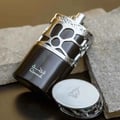 Lattafa Qimmah Eau De Parfum for Men 100ml — A black and silver perfume box with a pattern of irregular black shapes on a silver background, next to a black perfume bottle with a silver cap featuring a similar pattern. | Lattafa Qimmah Eau De Parfum for Men 100ml — Kotak minyak wangi hitam dan perak dengan corak