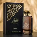 Lattafa Musk Al Aroos — A dark blue perfume bottle with gold Arabic calligraphy and 'MUSK AL AROOS LATTAFA' text, presented in an open dark blue gift box with a black velvet insert. | Lattafa Musk Al Aroos — Botol minyak wangi biru gelap dengan kaligrafi Arab emas dan teks 'MUSK AL AROOS LATTAFA', dipersembahkan dalam