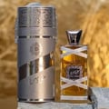 Lattafa Oud Mood Reminiscence 100ml — A cylindrical grey box with silver ornate patterns and a silver ribbon handle stands next to a clear glass perfume bottle with a silver cap, wrapped in white ribbon. | Lattafa Oud Mood Reminiscence 100ml — Kotak kelabu silinder dengan corak perak berhias dan pemegang reben perak