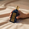 Hand holding Azeezah Lattafa blue gold fragrance elegant closeup side view