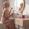 Perempuan berhijab pakai makeup dekat Charm LaMuse Lattafa edp meja solek