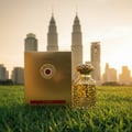 Emeer Lattafa woody scented gold perfume on grass kuala lumpur skyline view