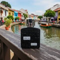 Lattafa ramz silver edp on wooden railing overlooking colourful buildings river malaysia daytime scene closeup