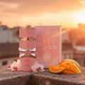 Yara Lattafa pink perfume bottle on stone surface surrounded sliced mango flowers sunset background